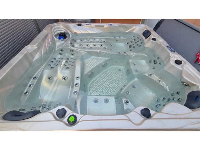 Cadă cu hidromasaj New Maximus, cu un design modern și o suprafață din acril transparent, având un interior cu 136 de jeturi de masaj, situată într-un mediu exterior, cu margini argintii și un fund transparent, oferind un aspect elegant și spațios.