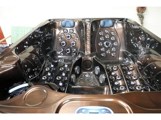Cadă cu hidromasaj PUMA 210×170×90 cm, cu un interior lucios de culoare espresso, dotată cu multiple jeturi de masaj, două șezlonguri ergonomice și un loc de ședere, amplasată într-un mediu interior confortabil.