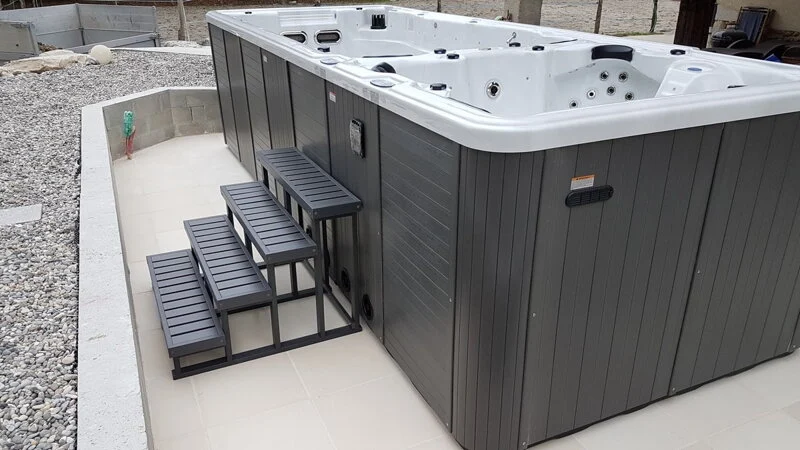 Spa & Swim Spa 801 este un spa de dimensiuni mari, cu un exterior de culoare gri și un interior alb, dotat cu scărițe negre din lemn, amplasat pe o platformă de plăci ceramice, înconjurat de pietriș.