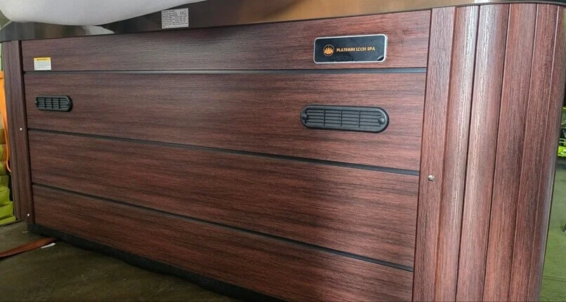 Cadă cu hidromasaj Aurora pentru 5 persoane, cu un design modern din material acrilic, având o carcasă de culoare maro și detalii negre, situată într-un mediu interior.